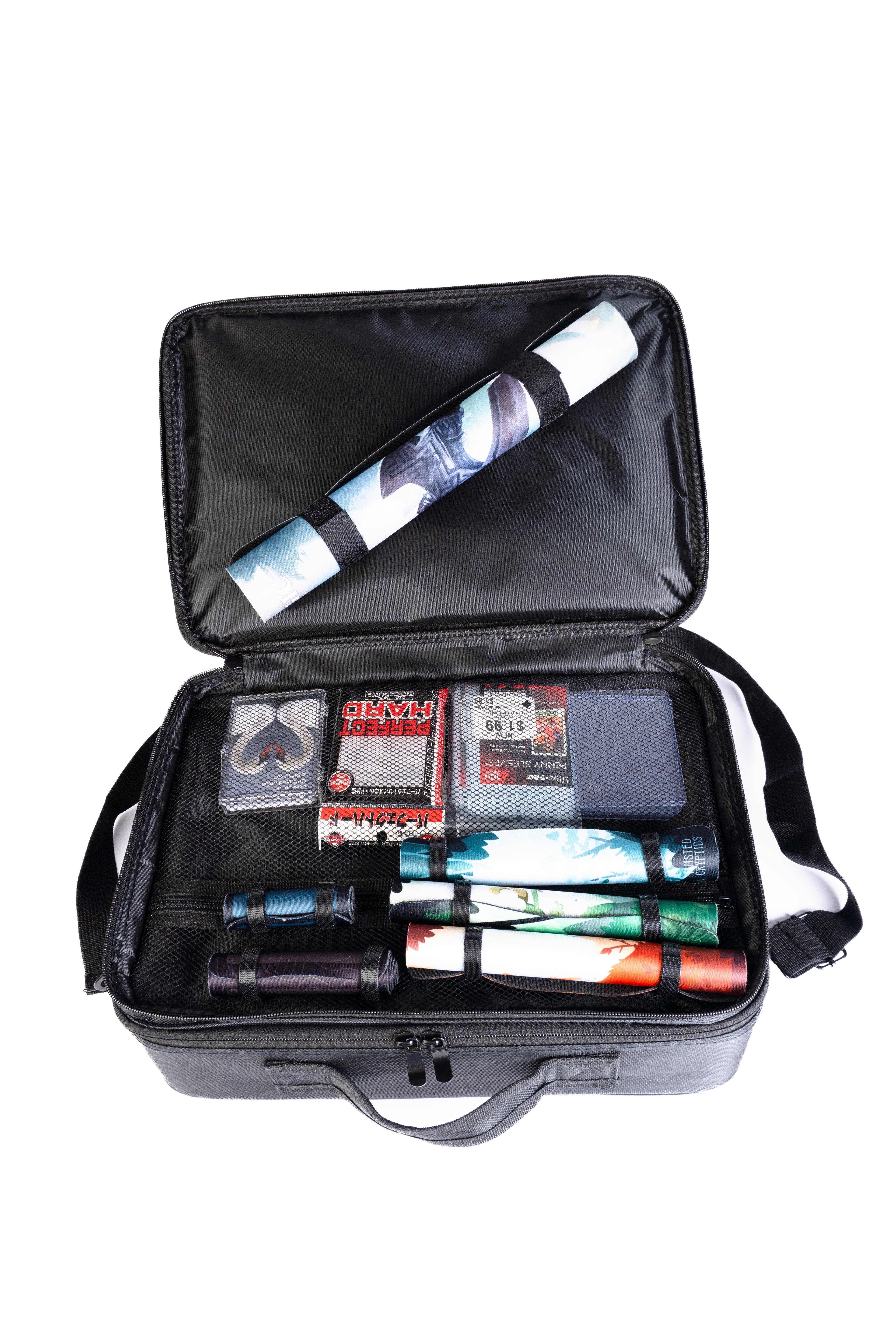 Open black modular bag with various items including a playmat and card boxes on a white background
